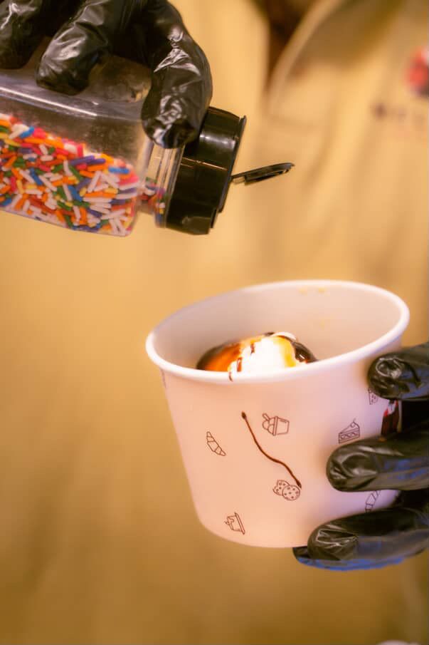 Topping a dessert with sprinkles at the cart